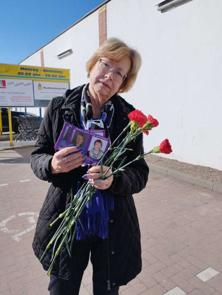 Rote Nelken verteilt Annegret vor dem EDEKA in Neukloster